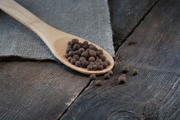 Black pepper on a wooden spoon on the background of the old table.