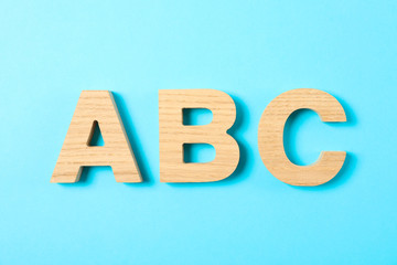 Wooden letters of English alphabet on color background, space for text