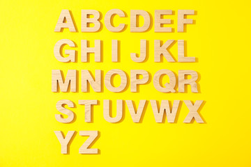 Wooden letters of English alphabet on color background, top view