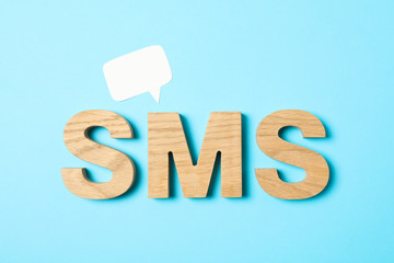 Word SMS lined with wooden letters on color background