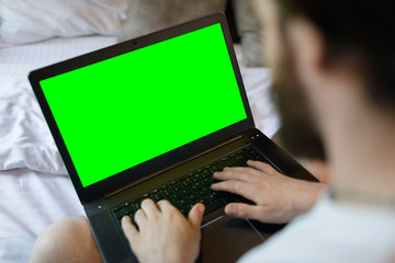 Fototapeta na wymiar Relaxed male on couch using green screen laptop