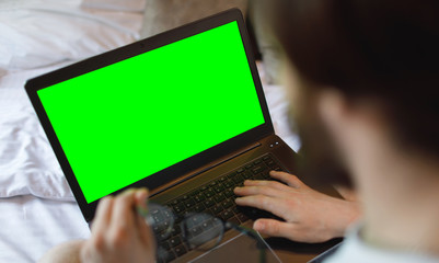 Fototapeta na wymiar Young man working on his laptop computer connected to wireless internet in his flat. Green screen.