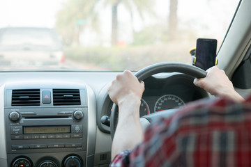Man sit in the car hand is driving the car on the road. travel to He is looking to a road traffic route and listening to music happily