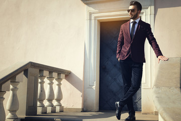 Elegant fashionable man in black sunglasses posing outdoor on the stairs (copy space).