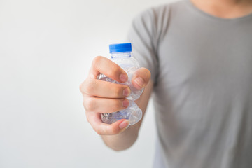 Hand holding a recyclable plastic bottles on white background.