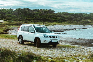 Fototapeta na wymiar white suv car at rocky seaside. off road car travel concept