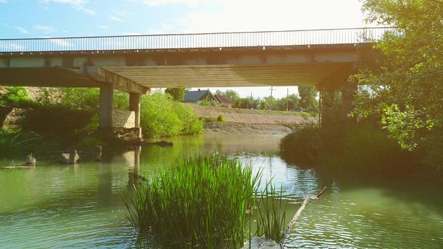 Low aerial view of a river and a bridge over it. 4K.