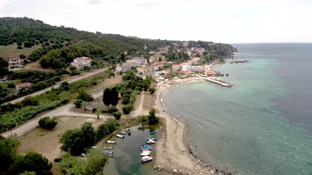Aerial view of a small natural harbor and a small beach with a pier in the area of Agia Paraskevi in Halkidiki Greece, move forward by drone