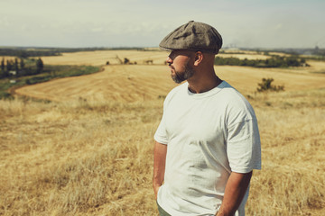 man in a t-shirt and a cap on the background of cereal fields
