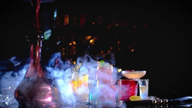 Two hookahs stand on the bar counter in a hookah bar in the dark, slow motion. smoking hookah at the bar with cocktails
