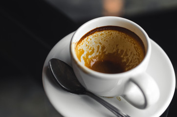 close up modern hot black coffee the espresso on dark background with coffee bubble foam pattern and texture in empty white cup looking and feel so delicious on glasses table in coffee shop.