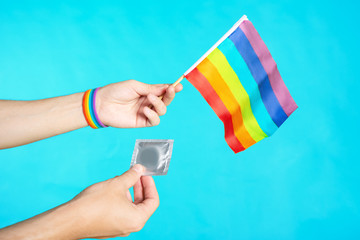 Hand with LGBT bracelet holding a condom. The concept of safe sex life for gay lesbian and transgender people