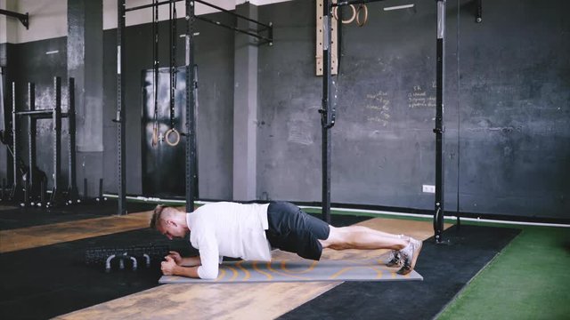 High performance triathlon or marathon exercises. Man in good fit does plank alternating leg lifts for improving sports training. Available exercises for office workers. Intermediate no equipment