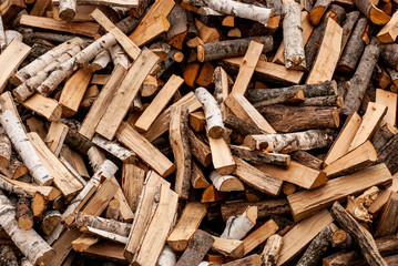 Split dry firewood ready for winter. Background of logs, birch, pine and oak