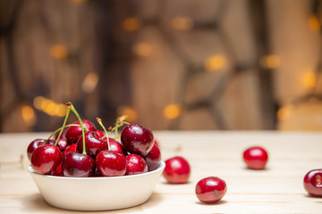 Fresh cherries in the white bowl on wood table