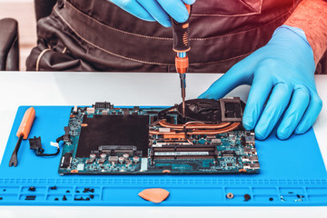 The repairman works in technical support, is engaged in the restoration and cleaning of the laptop.