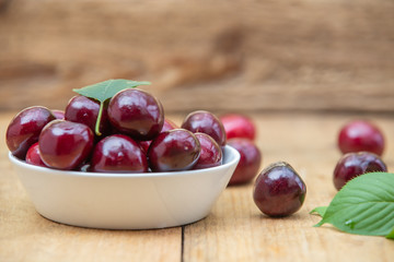 Fresh cherries in the white bowl on wood table