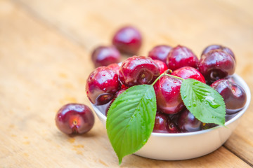 Top view fresh cherries in the white bowl on wood table