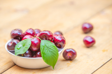 Top view fresh cherries in the white bowl on wood table