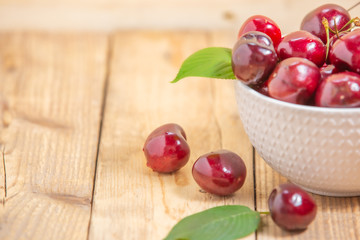 Fresh cherries in the white bowl on wood table