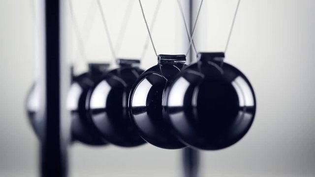 The chrome balls of a Newton&rsquo;s Cradle colliding in slow motion