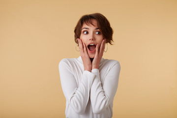 Cute happy amazed short haired young woman in blank t-shirt, loks surprised with wide open mouth,...