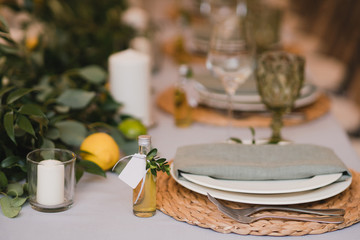 Coziness and style. Modern event design. Table setting at wedding reception. Floral compositions with beautiful flowers and greenery, candles, laying and plates on decorated table.