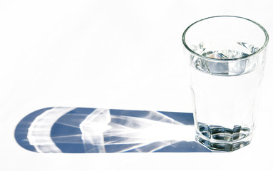 Water glass with strong shadows on white background