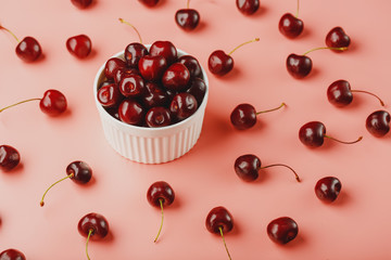 Cherry berry on a pink background in a white cup, top view.