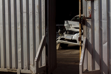Blurred accident white car waiting for repair in the garage shop with opening strong corrugated metal sheet door and brightness sunlight background.
