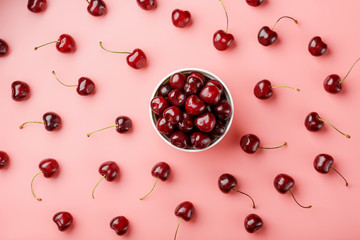 Cherry berry on a pink background in a white cup, top view.
