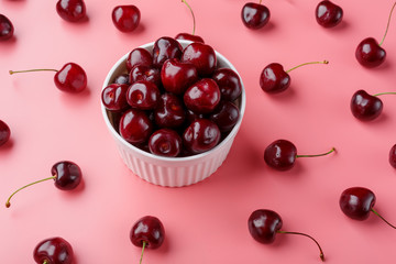 Cherry berry on a pink background in a white cup, top view.