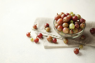Red and green gooseberries, ripe berries on table in plate.