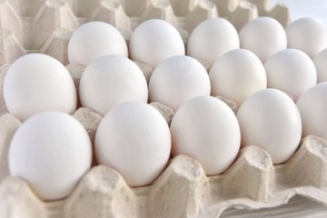 White organic hen eggs in carton recycling cardboard box on neutral background, selective focus. Dozen of raw farm chicken egg in carton box. Ingredient for delicious healthy breakfast. Easter symbol 