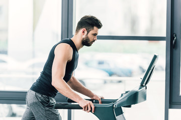 handsome sportsman running on treadmill at sports center