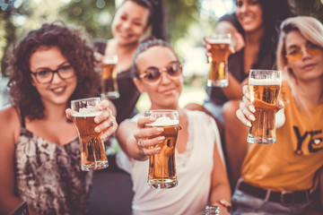 Happy group of best female friends drinking beer - Friendship concept with young female friends enjoying time and having genuine fun at outdoor nature ambient
