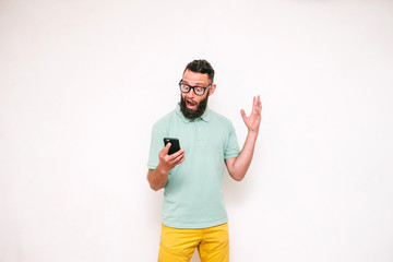 Naklejka premium Portrait of young man looking at mobile phone isolated over white background,