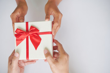 a asian man gives a box of gift with red ribbon to a woman making surprise, during christmas celabration and a new year with love, happiness, cheer  and joyful on issolated background