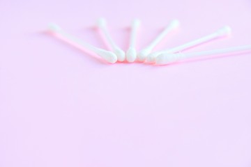 Group of white personal cotton swab with selective focus on pink neutral background with empty space for text. White hygienic cotton buds for daily routine. Soft cotton ear sticks. Health care tools 