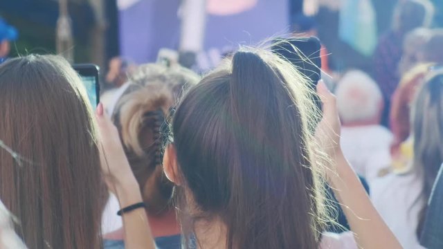 Two young women shooting on smartphones. Close-up.