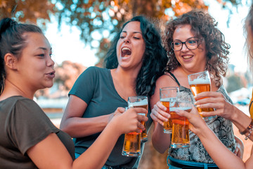 Happy group of best female friends drinking beer - Friendship concept with young female friends enjoying time and having genuine fun at outdoor nature ambient