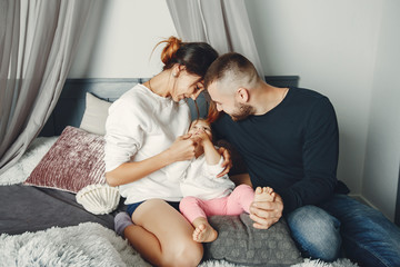 Cute family at home. Beautiful mother in a white sweater. Father with little daughter.