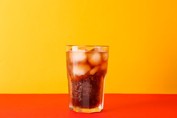 Glass of cold cola against color background, space for text