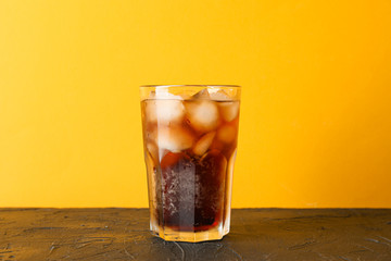 Glass of cold cola against color background, space for text
