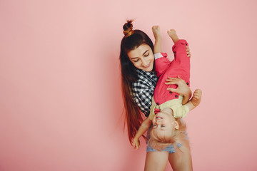 Stylish mother in a shirt and shorts. Little girl in a fashion clothes. Family have fun in a studio