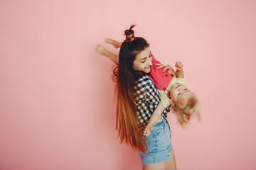 Stylish mother in a shirt and shorts. Little girl in a fashion clothes. Family have fun in a studio