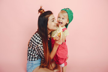 Stylish mother in a shirt and shorts. Little girl in a fashion clothes. Family have fun in a studio
