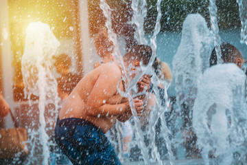 The child plays in the fountain in the hot summer