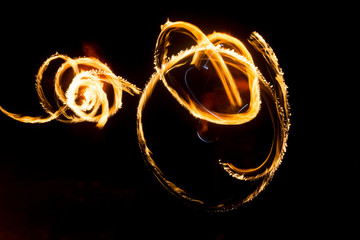 The artist shows a fire show at night spinning torches, circles of fire and loops