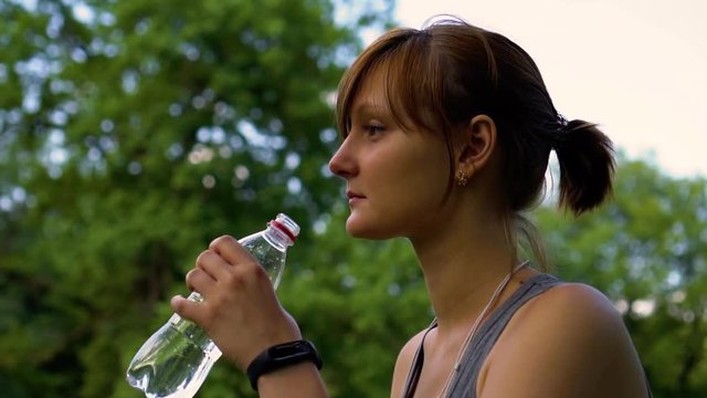 girl in nature is drinking clean water